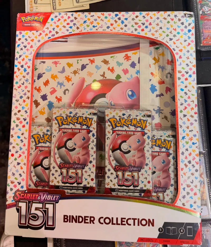 A sealed Pokémon 151 binder collection box on a vendor table