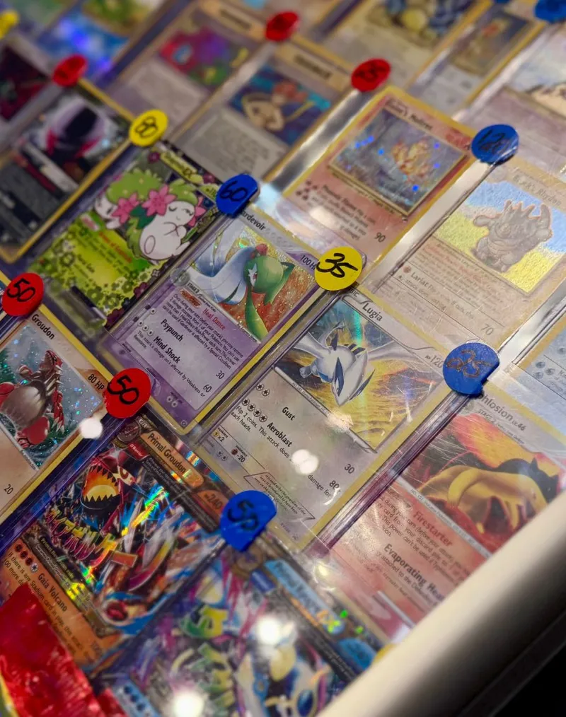 Raw and graded Pokémon singles with price stickers in a vendor's glass case