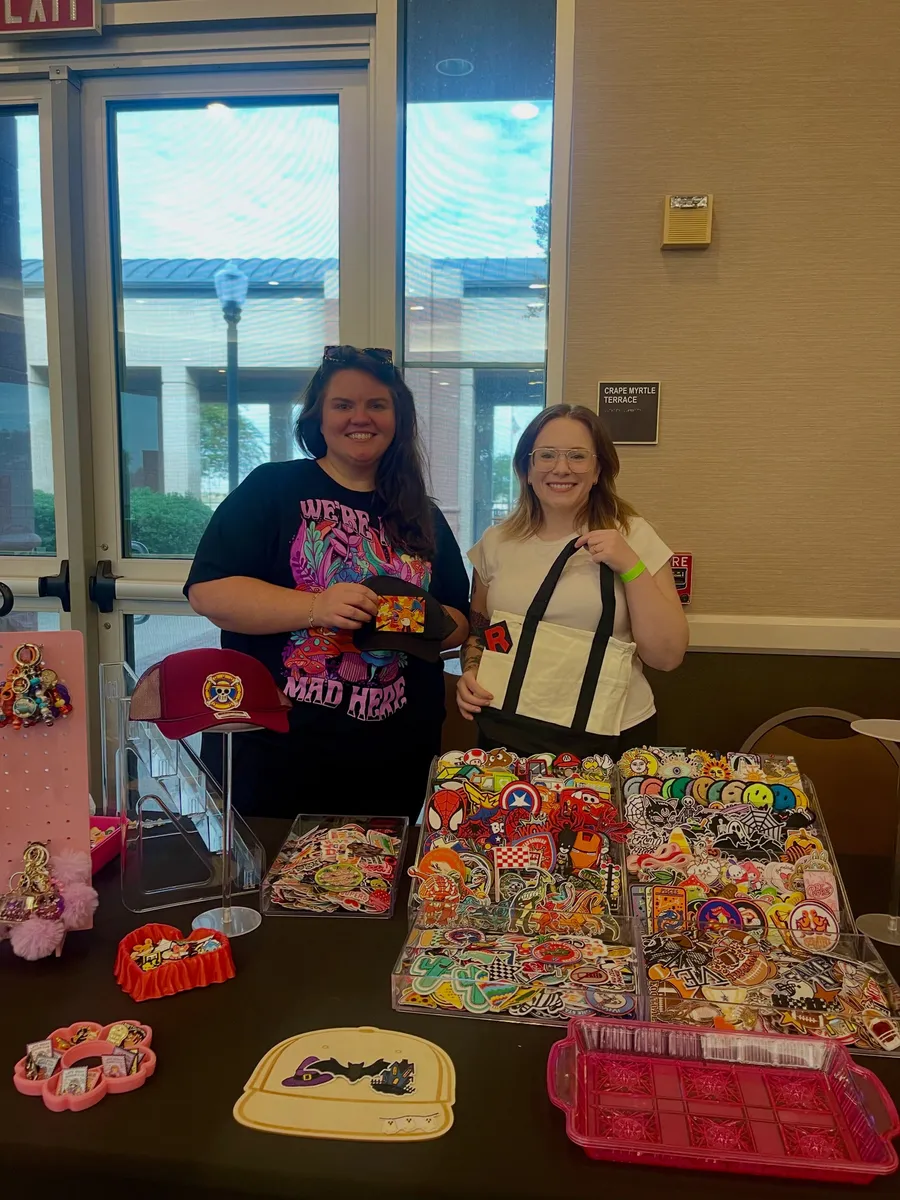 Two vendors behind a table covered in embroidered patches